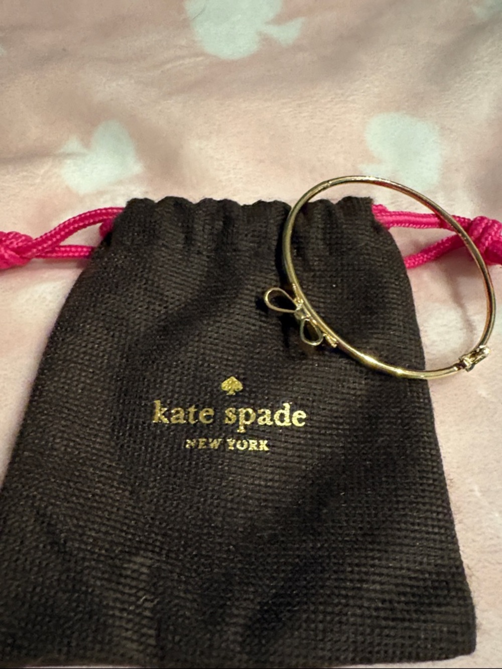 kate spade gold bow bangle with pink drawstring pouch